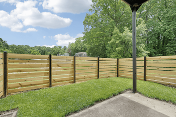 A wooden fence in a backyard with grass and trees